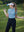 Model in sky blue women's performance solid polo holding a golf club outdoors