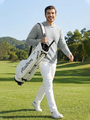 Model holding a golf bag on a golf course, wearing light grey heather texture solid hoodies pullover in full-body view.