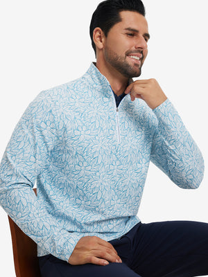 Model seated on chair, wearing full print quarter zip pullover in blue artichoke, casual upper body view.