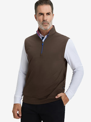 Model with hands in pockets, wearing print collar quarter zip golf vest in coffee brown, casual look.