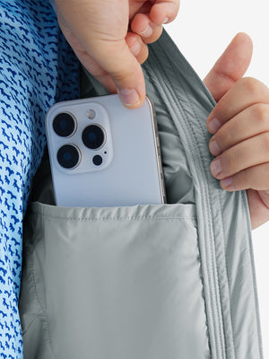 Close detail of hands inside pockets of boys windproof puffer jacket with pockets in light grey.