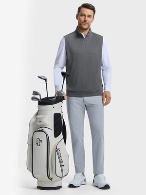 Front full body shot of model wearing black melange lightweight sleeveless quarter zip golf vest with one hand resting on golf bag