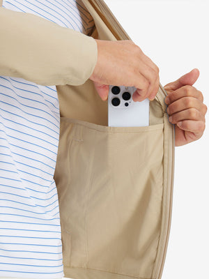 Hand placing iPhone into inner pocket of lightweight water-resistant outerwear jacket in beige