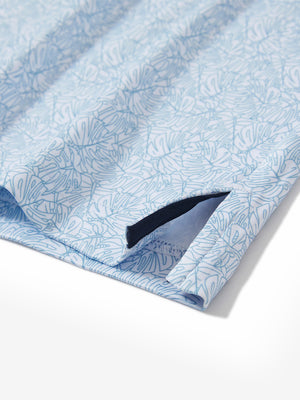 Close-up of the hem vent on the light blue line leaf 4 way stretch print collared polo shirt, showing the side split for movement