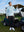Model in black stretch plain everyday pants standing next to a golf cart, full-body shot