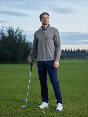 Model leaning on a golf club on course, styled in quarter zip melange pullover with relaxed black grey heather tone