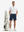 Full-body front view: model in white moisture-wicking short sleeve henley shirt with golf bag.