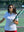 Model in white women's performance solid polo holding a badminton racket outdoors, waist-up shot