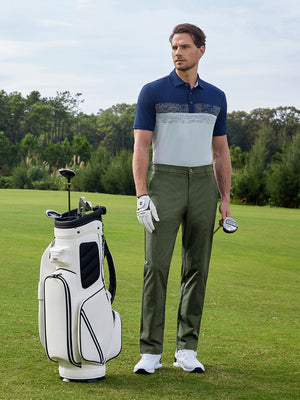 Model leaning on a golf bag on course, stretch plain everyday pants in olive green with clean style